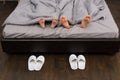 Close up of male and female feet under grey blanket, near two pa Royalty Free Stock Photo