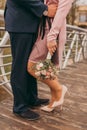 Close up male and female legs, newlywed standing on a wooden bridge and bride holding a bouquet. Wedding day Royalty Free Stock Photo