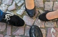 Four feet in formal shoes on historical cobblestones. Top view