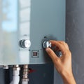 Close-up of male hand adjusting temperature of water heater. Modern home gas fired boiler. Royalty Free Stock Photo