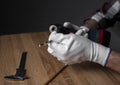 Close up male hand in gloves holding metal auger and putting it on drill tool over wooden desk