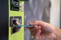 close-up of male hand hold credit card, young man using device bank terminal for cash dispensing, exchanging money in payment Royalty Free Stock Photo