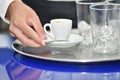 View of male hand holding a cup of coffee over a bar tray with glasses on it. Bartending and coffee concept