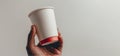 Close up of male hand holding a disposable coffee paper cup isolated on light grey background. Mockup with copy space Royalty Free Stock Photo