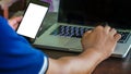 Close up male hand holding phone white screen over background of laptop, on wooden background. Royalty Free Stock Photo