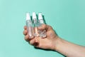 Close-up of male hand holding portable plastic dispenser bottles with sanitizer antiseptic, antibacterial gel, against coronavirus