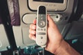 Close up male hand is holding remote control of LCD screen monitor in an airplane seat for passengers entertainment Royalty Free Stock Photo