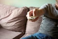 Close up of male hand holding remote control, man watching TV while sitting on the couch at home, using remote control to change Royalty Free Stock Photo