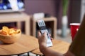 Close up of male hand holding remote control while watching TV at home Royalty Free Stock Photo