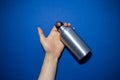 Close-up of male hand holding reusable aluminum thermo water bottle isolated on phantom blue of color. Royalty Free Stock Photo