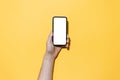 Close-up of male hand holding smartphone with empty white mockup, isolated on yellow background. Royalty Free Stock Photo