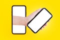 Close-up of male hand holding smartphone with mockup, comes out of the screen of other smartphone. Background of yellow color.. Royalty Free Stock Photo