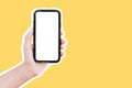 Close-up of male hand holding smartphone with mockup, isolated with white contour on yellow background. Royalty Free Stock Photo