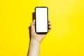 Close-up of male hand holding smartphone with  mockup, isolated on yellow background. Royalty Free Stock Photo