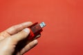 Close-up of male hand holding usb flash adapter for sd card isolated on background of red color. Royalty Free Stock Photo