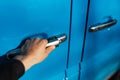 Close-up of male hand, opens the chrome door handle of blue car. Royalty Free Stock Photo