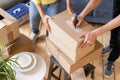 Close up of hand packing cardboard box, concept moving house. Young couple moving to a new apartment together