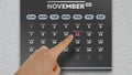 Close-up of a male hand pointing finger to the Veterans Day date on the November page of a wall calendar 2021
