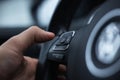 Close-up of male hand presses button of phone on steering wheel of car. Royalty Free Stock Photo