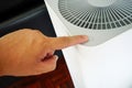 Close up of hand pressing button of air purifier placed on wooden floor Royalty Free Stock Photo