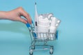 Close-up of male Hand With Shopping Cart full of pills at blue background. The concept of the medicine of online shopping. Copy