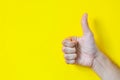 Close up of male hand showing thumbs up sign over yellow background with copy space, flat lay Royalty Free Stock Photo