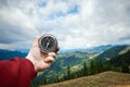 Close-up Male hand and silver compass on a background of mountain landscape. The concept of travel, hiking, help, searching,