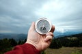 Close-up Male hand and silver compass on a background of mountain landscape. The concept of travel, hiking, help, searching,