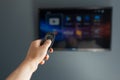 Close-up of male hand using remote of modern smart tv on background of television. Royalty Free Stock Photo