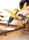 Close-up of a male hand and a yellow screwdriver. A man makes a big hole in the board with a special tool.