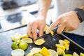 Male hands slicing lemons and limes on a black tray Royalty Free Stock Photo