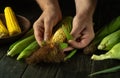 Close-up of male hands cleaning corn cobs on kitchen table. Concept of cooking vegetarian food Royalty Free Stock Photo