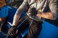 Close-up of male hands in gloves pulling rope of sailboat while mooring yacht and sitting with friends on deck.