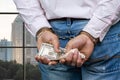 Close up male hands in handcuffs holding money.