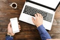 Casually dressed student / blogger / writer / man working on pc laptop, typing on keyboard, writing blog article, drinking in coff Royalty Free Stock Photo