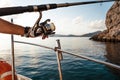 Close up of male hands holding fishing rod while fishing on sailboat in open sea Royalty Free Stock Photo