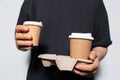 Close-up of male hands holding a paper coffee cup and holder for cups takeaway.