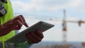 Close up of male hands holding tablet gadget tapping and scrolling on screen outdoors. Man builder engineer in uniform