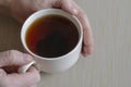 Close-up of male hands and a mug with tea on a beige surface