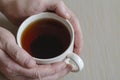 Close-up of male hands and a mug with tea on a beige surface