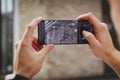 Close-up male hands of a photographer hold a smartphone horizontally and take pictures of CCTV cameras on the corner of