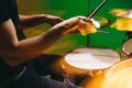 Close-up of male hands playing drums isolated on green-red background in neon