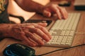 Close-up of male hands typing on computer keyboard with mouse and smartphone Royalty Free Stock Photo