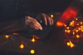 Close-up of male hands typing on keyboard of laptop in dark room with garlands. Royalty Free Stock Photo