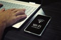 Close up of male hands typing on laptop keypad and checking the smartphone wi-fi connection. Cellphone with signal icon Royalty Free Stock Photo