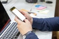 Close up of male hands using mobile phone blank white color copy space for your text message with laptop in cafe on white desk Royalty Free Stock Photo