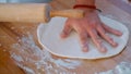 Close up male hands using rolling-pin flatten dough making pizza