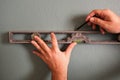 Close up of male hands using spirit level and pencil to mark straight line on wall. Home renovation concept Royalty Free Stock Photo