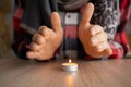 Close-up of male hands warming up near a burning candle which stands on the table. concept of problems with heating Royalty Free Stock Photo