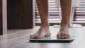 Close-up male legs stand on electronic automatic scales weight control unrecognizable man checks body heft after